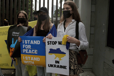 Pengunjuk rasa yang tergabung dalam Solidaritas untuk Rakyat Ukraina membentangkan bendera Ukraina saat aksi damai di depan Kedutaan Besar Rusia.