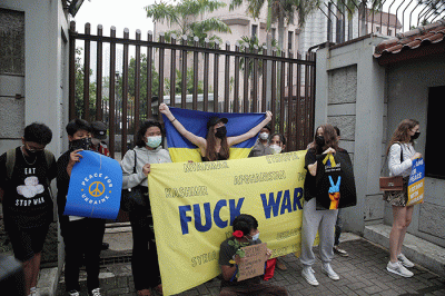 Pengunjuk rasa yang tergabung dalam Solidaritas untuk Rakyat Ukraina membentangkan bendera Ukraina saat aksi damai di depan Kedutaan Besar Rusia.