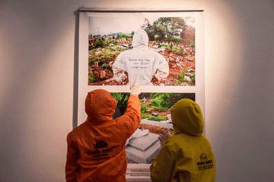 Pengunjung pameran mengenakan pakaian hazmat yang disediakan saat berkunjung ke pameran foto 731 yang diselenggarakan oleh Pewarta Foto Indonesia Bandung.