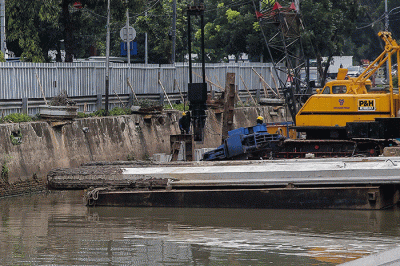 Pekerja menyelesaikan pemasangan dinding turap di kali pasar baru, Jakarta, Sabtu (12/3/2022).