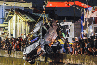 Petugas mengevakuasi mobil jenis Daihatsu Xenia bernomor polisi BG 1162 RR warna silver dari dalam sungai Jembatan Gledek, Palembang, Minggu (13/3/2022).