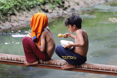 Sejumlah anak menikmati makanan dan bermain di Kali Gresik, Menteng, Jakarta, Senin (14/3/2022).