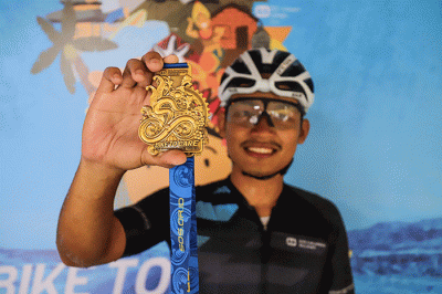 Peserta Bike To Care 2022 #BaliLoop 500 Km menunjukkan medali usai melintasi garis finish etape dua di Sol Benoa, Badung, Bali, Minggu (20/3/2022).
