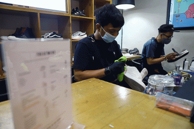 Pekerja membersihkan sepatu pelanggan di Cleaning Shoes Kicks Kemon, Haji Nawi, Jakarta Selatan, Sabtu (26/3/2022).