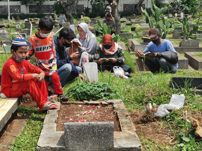 Peziarah memanjatkan doa di makam keluarga dan kerabat di Taman Pemakaman Umum (TPU) Karet Bivak, Jakarta, Minggu, (27/3/2022).