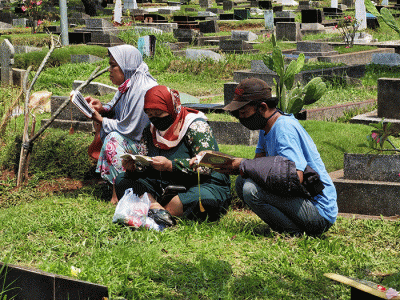 Peziarah memanjatkan doa di makam keluarga dan kerabat di Taman Pemakaman Umum (TPU) Karet Bivak, Jakarta, Minggu, (27/3/2022).