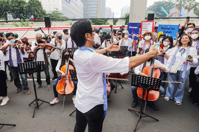 Komposer Addie MS menjadi konduktor orkestra saat menggelar seruan aksi damai di Depan Kedutaan Besar Rusia di Kuningan, Jakarta Selatan, Rabu (30/2/2022).