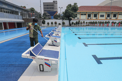 Petugas membersihkan dan merawat area kolam renang di Gelanggang Remaja Jakarta Selatan (GRJS) Bulungan, Kebayoran Baru, Jakarta, Kamis (31/3/2022).