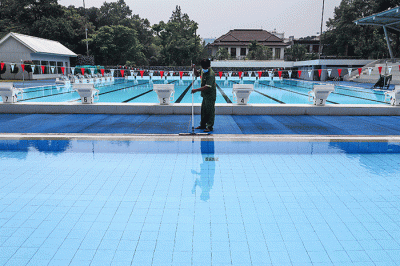 Petugas membersihkan dan merawat area kolam renang di Gelanggang Remaja Jakarta Selatan (GRJS) Bulungan, Kebayoran Baru, Jakarta, Kamis (31/3/2022).