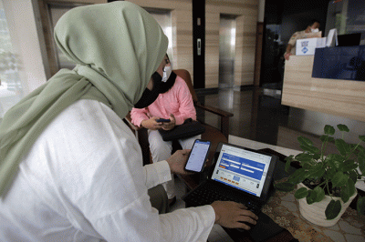 Pekerja kantoran saat membuka aplikasi KAI Access untuk membeli tiket kereta mudik di kawasan Jakarta Pusat, Senin (4/4/2022).