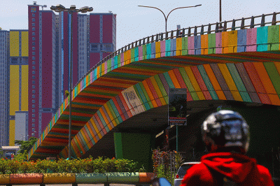 Pengendara melintas berlatar belakang gedung RSDC Wisma Atlet Kemayoran, Jakarta Pusat, Kamis (14/4/2022).
