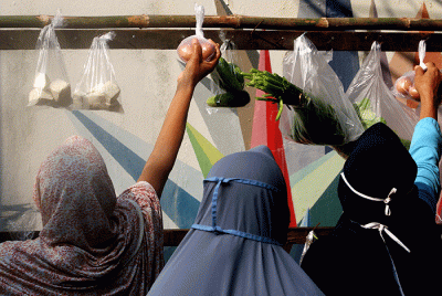 Warga mengambil sayuran, lauk pauk dan baju bekas gratis hasil sumbangan Warga RT 002 RW 04 dan para donatur di Jalan Jati Padang VI, Jakarta.