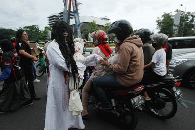 Aksi sekumpulan orang berkostum hantu yang tergabung dalam komunitas Semarangker membagi-bagikan takjil kepada pengguna jalan.