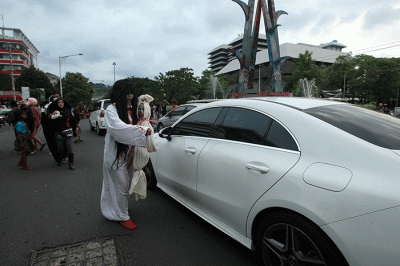 Aksi sekumpulan orang berkostum hantu yang tergabung dalam komunitas Semarangker membagi-bagikan takjil kepada pengguna jalan.