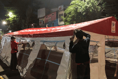 Petugas pemadam kebakaran bersama petugas Palang Merah Indonesia mendirikan tenda darurat untuk warga yang menjadi korban kebakaran di kawasan Pasar Gembrong.