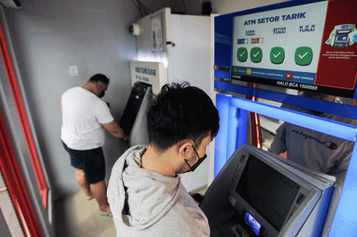 Warga saat melakukan penarikan uang tunai di Anjungan Tunai Mandiri (ATM) kawasan Pinang Ranti, Jakarta Timur, Selasa (10/5/2022).