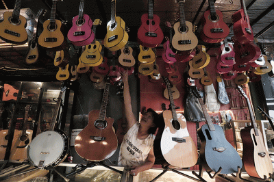 Penjual mencoba gitar di toko Eagle Music di kawasan Setu, Jakarta Timur, Sabtu (14/5/2022).