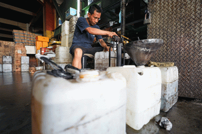 Penjual memasukkan minyak goreng curah ke dalam jerigen di Kawasan Pasar Cipete, Jakarta Selatan, Jumat (20/5/2022).