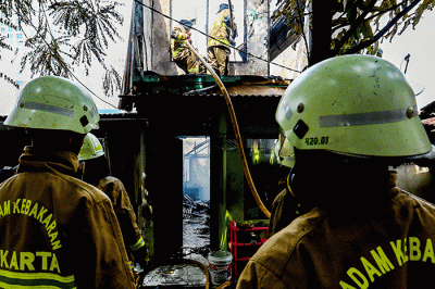 Petugas pemadam kebakaran berusaha memadamkan api yang membakar rumah warga di Jalan Masjid Alhuda atau depan Stasiun Kebayoran Lama.