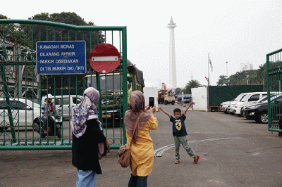 Warga berfoto dengan latar belakang Monumen Nasional di Jakarta, Kamis (26/5/2022).