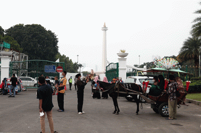 Warga berfoto dengan latar belakang Monumen Nasional di Jakarta, Kamis (26/5/2022).