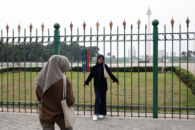Warga berfoto dengan latar belakang Monumen Nasional di Jakarta, Kamis (26/5/2022).