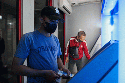 Seorang warga menunjukkan uang sebelum melakukan setor tunai di salah satu Anjungan Tunai Mandiri (ATM) kawasan Jakarta Timur, Kamis, (9/6/2022).