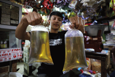 Pedagang menunjukkan minyak goreng curah di Pasar Kebayoran Lama, Jakarta, Senin (13/6/2022).