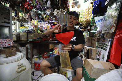 Pedagang menunjukkan minyak goreng curah di Pasar Kebayoran Lama, Jakarta, Senin (13/6/2022).