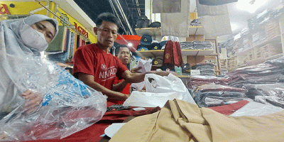 Penjual seragam sekolah melayani pembeli di Pasar Pondok Gede, Kota Bekasi, Jawa Barat, Jumat (8/7/2022).
