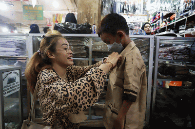 Orang tua memilih seragam sekolah baru untuk anaknya di salah satu kios di Pasar Kebayoran Lama, Jakarta, Sabtu (9/7/2022).