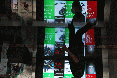 Karyawan melintas di depan layar pergerakan indeks harga saham gabungan (IHSG) di Bursa Efek Indonesia (BEI), Jakarta, Senin (11/7/2022).