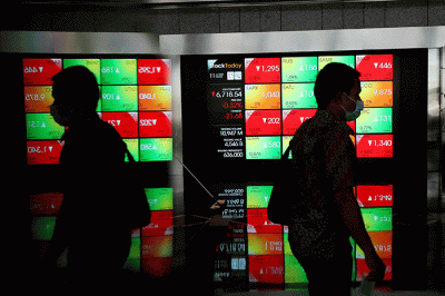 Karyawan melintas di depan layar pergerakan indeks harga saham gabungan (IHSG) di Bursa Efek Indonesia (BEI), Jakarta, Senin (11/7/2022).