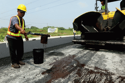 Pekerja menyelesaikan proyek pengaspalan plastik di kawasan BSD City, Tangerang, Banten, Kamis (21/7/2022).