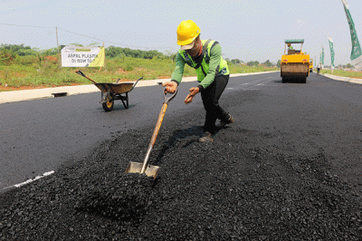 Pekerja menyelesaikan proyek pengaspalan plastik di kawasan BSD City, Tangerang, Banten, Kamis (21/7/2022).