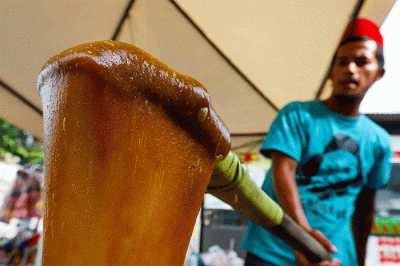Pengunjung saat mencoba mengaduk dodol Betawi di Festival Rawa Belong, Jakarta Barat, Minggu (14/8/2022).