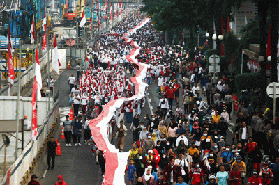 Ratusan warga kompak membawa Bendera Merah Putih sepanjang 1.700 meter di Jakarta, Minggu (28/8/2022).