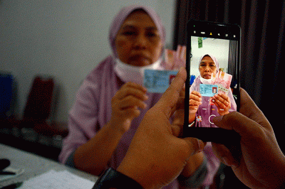 Warga menunjukan uang senilai Rp 300.000 saat pembagian Bantuan Langsung Tunai (BLT) subsidi Bahan Bakar Minyak (BBM) di kawasan Gambir, Jakarta.