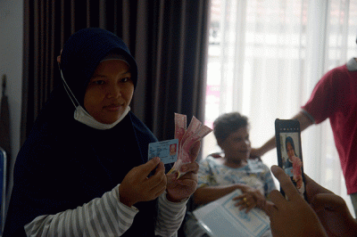 Warga menunjukan uang senilai Rp 300.000 saat pembagian Bantuan Langsung Tunai (BLT) subsidi Bahan Bakar Minyak (BBM) di kawasan Gambir, Jakarta.