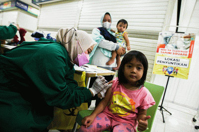 Petugas medis saat memberikan suntikan vaksin campak-rubella untuk Anak dalam program Bulan Imunisasi Anak Nasional (BIAN) di Mal Tamini Square.