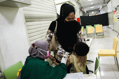 Petugas medis saat memberikan suntikan vaksin campak-rubella untuk Anak dalam program Bulan Imunisasi Anak Nasional (BIAN) di Mal Tamini Square.