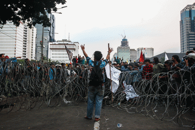 Massa aksi menghindar dari kobaran api saat demo menolak kenaikan BBM di kawasan Patung Kuda, Monas, Jakarta Selasa (13/9/2022).