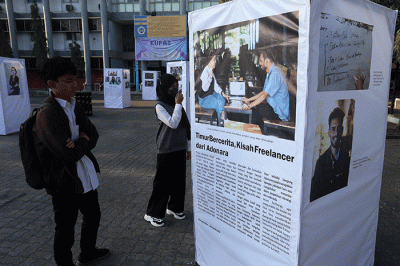 Pengunjung mengamati foto cerita karya Unit Kegiatan Mahasiswa (UKM) Communication Photography Club (CIPHOC).
