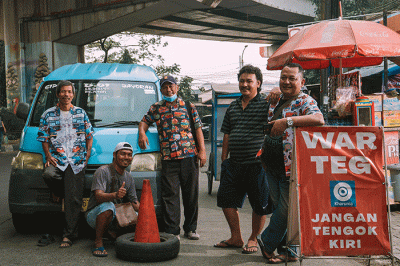 Sejumlah sopir berpose mengenakan pakaian bermotif yang diangkat dari ragam lukisan di belakang truk dan angkutan, Rabu (21/9/2022).