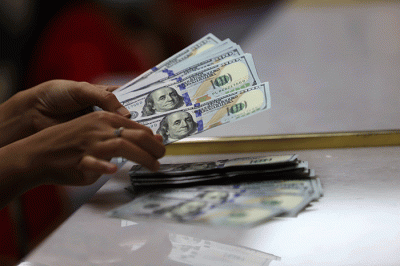 Petugas menunjukan uang pecahan dolar dan rupiah di Jakarta, Senin (3/10/2022).