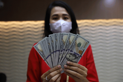 Petugas menunjukan uang pecahan dolar dan rupiah di Jakarta, Senin (3/10/2022).