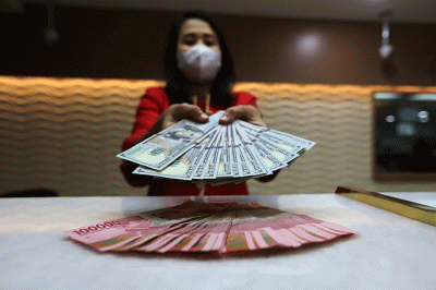 Petugas menunjukan uang pecahan dolar dan rupiah di Jakarta, Senin (3/10/2022).