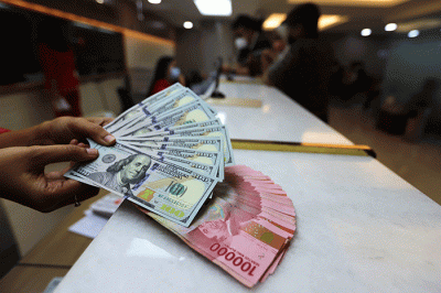Petugas menunjukan uang pecahan dolar dan rupiah di Jakarta, Senin (3/10/2022).