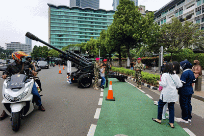 Warga berfoto di depan sejumlah alat utama sistem persenjataan atau alutsista milik TNI yang dipamerkan didepan Istana dan Bundaran Hotel Indonesia.