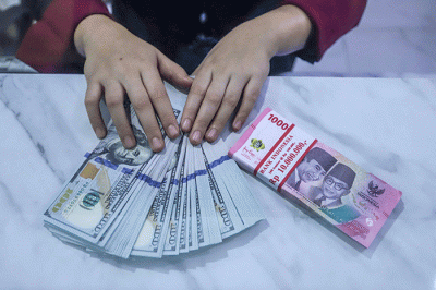 Petugas menunjukkan mata uang Rupiah dan Dolar AS di tempat penukaran uang Dolar Indo, Jakarta, Selasa (11/10/2022).